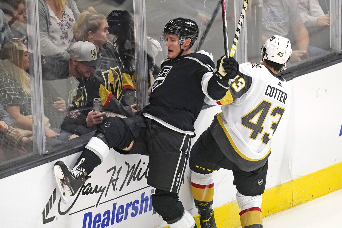 Los Angeles Kings defenseman Austin Strand, left, takes a hit from Vegas Golden Knights center ...