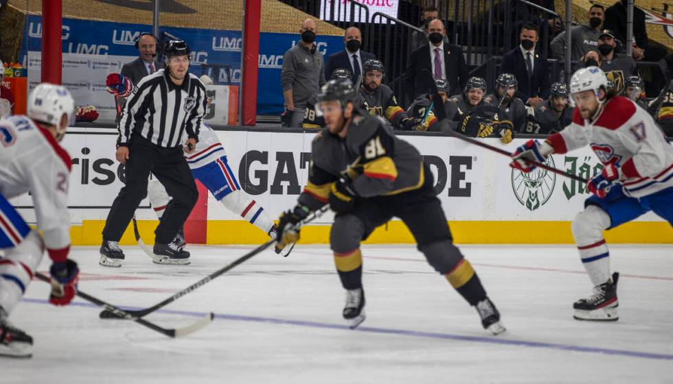 A referee looks on as Golden Knights center Jonathan Marchessault (81) drives the puck past Mon ...