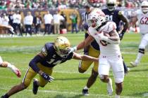 Wisconsin running back Chez Mellusi carries the ball as Notre Dame safety Kyle Hamilton comes u ...