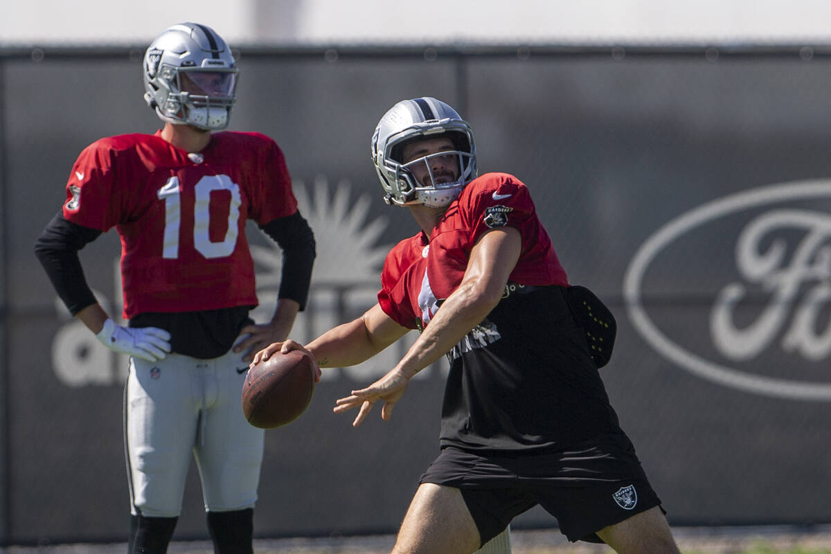 Raiders quarterback Kyle Sloter looks on as Raiders quarterback Derek Carr (4) prepares to thro ...