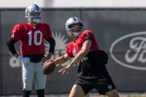 Raiders quarterback Kyle Sloter looks on as Raiders quarterback Derek Carr (4) prepares to thro ...