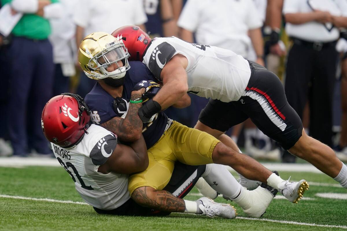 Notre Dame's Kyren Williams (23) is tackled by Cincinnati's Curtis Brooks (92) and Joel Dublank ...