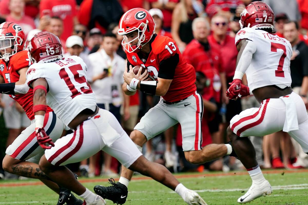 Georgia quarterback Stetson Bennett (13) tries to run past Arkansas defensive backs Simeon Blai ...