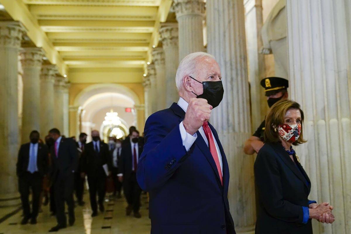 President Joe Biden gestures as he walks with House Speaker Nancy Pelosi of Calif., on Capitol ...