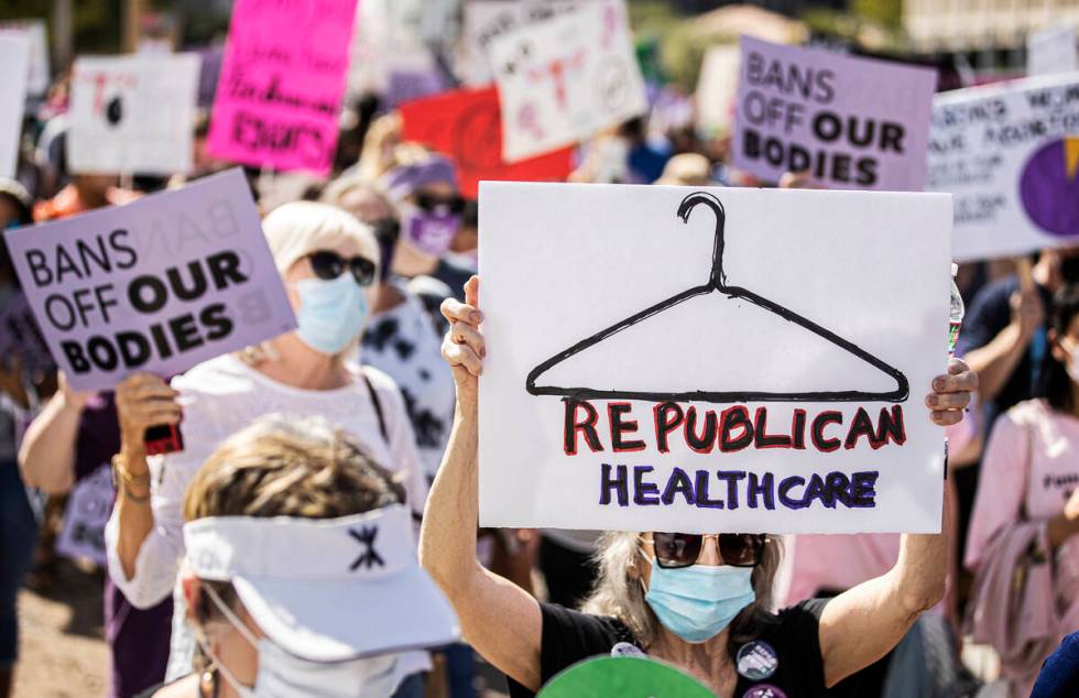 Demonstrators march down South Las Vegas Boulevard past the Lloyd D George Courthouse during a ...