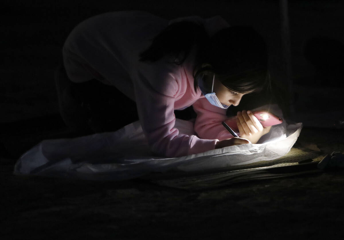Allexa Garcia, 8, of Los Angeles writes on her lantern at the Rise Festival in the Mojave Deser ...
