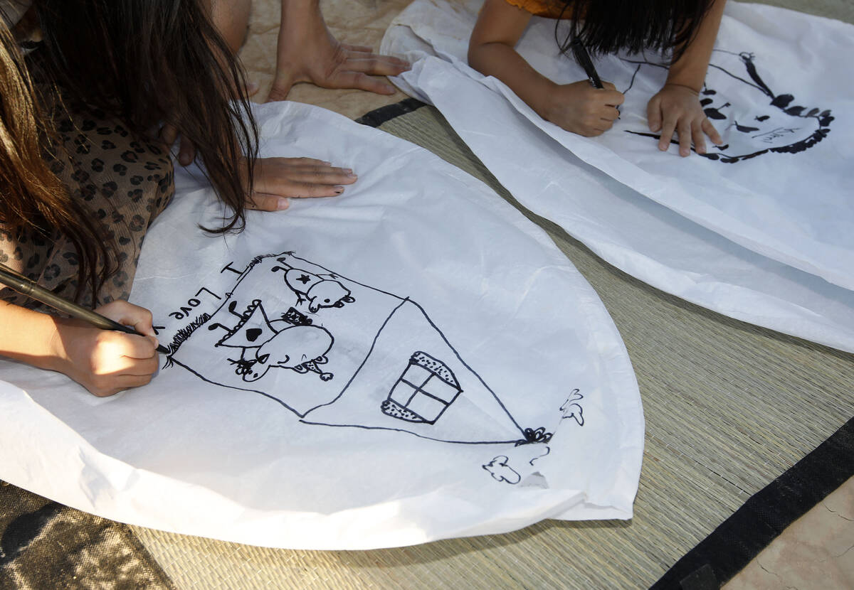 Yumi Yuan, 8, of Los Angles, left, and her sister Kimi Yuan, 4, draw pictures on their lantern ...