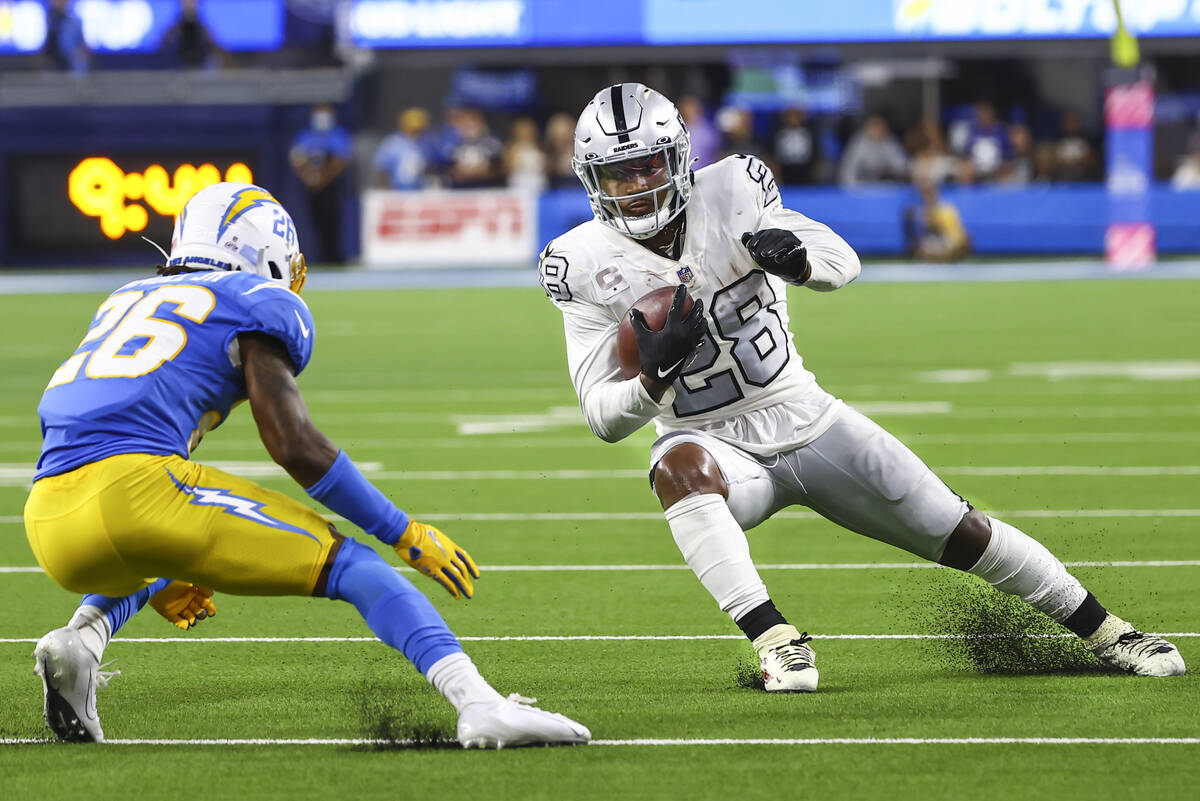 Raiders running back Josh Jacobs (28) looks to get past Los Angeles Chargers cornerback Asante ...
