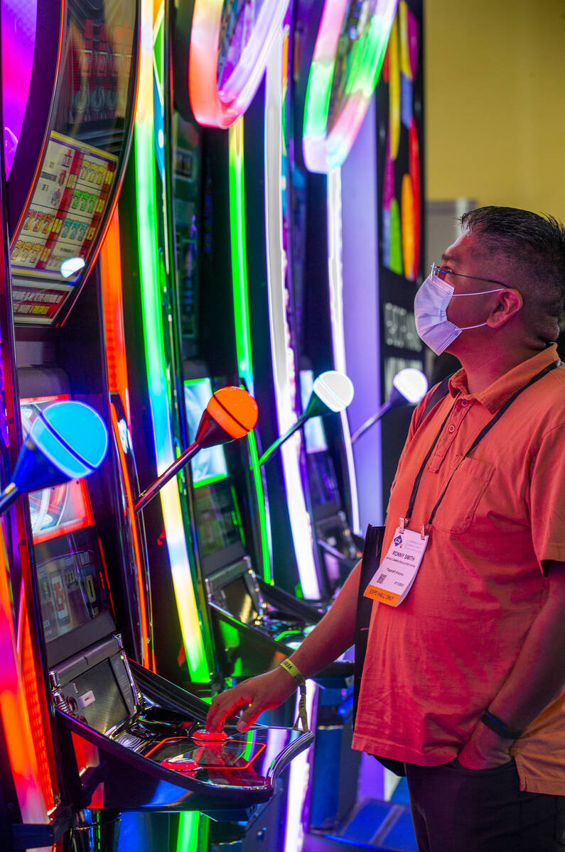 Attendee Ronny Smith plays a slot game in the IGT display space during day 3 at the Global Gami ...