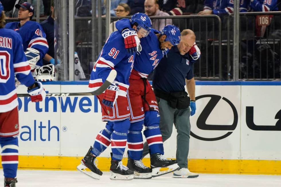 New York Rangers' Sammy Blais (91) and a trainer help Ryan Reaves off the ice after he was inju ...