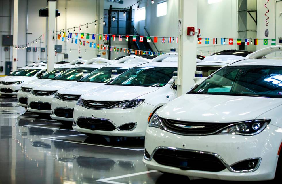 Modified Pacificas are parked in the open warehouse within the Motional autonomous vehicle head ...