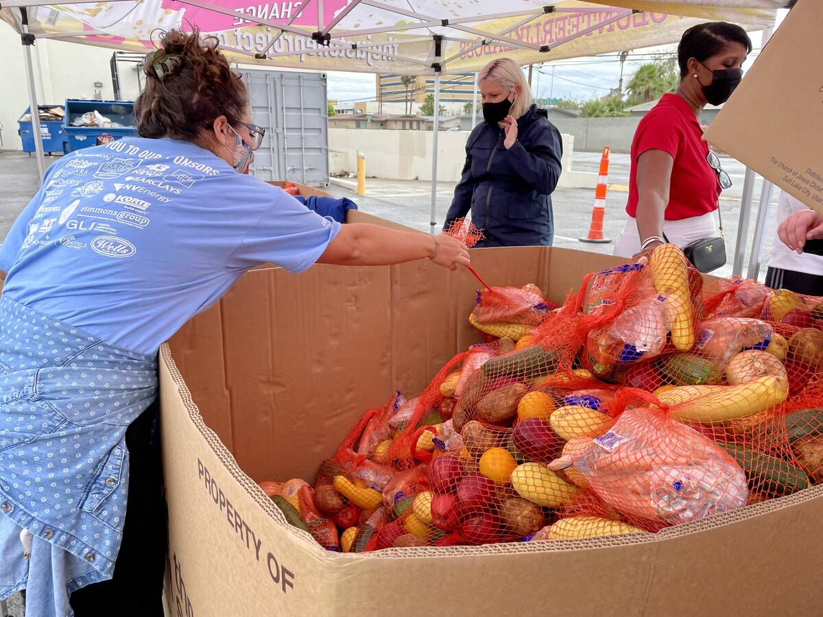 A volunteer at the Just One Project grabs a bag of produce during United Way of Southern Nevada ...