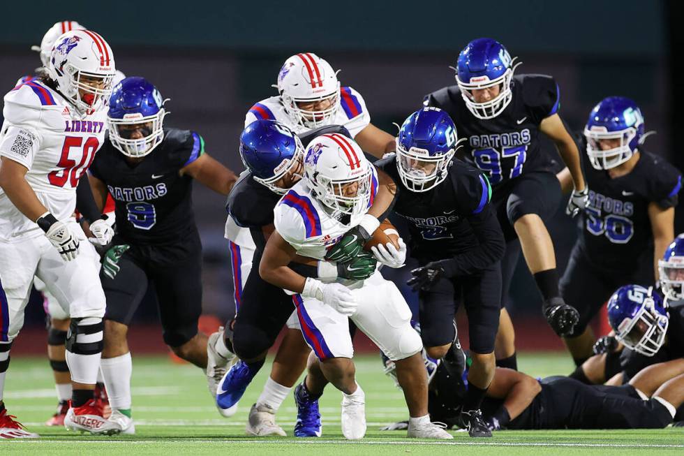 Liberty's Isaiah Lauofo (19) is tackled by Green Valley's Kendall Ayersman (2) and Herbert Ware ...