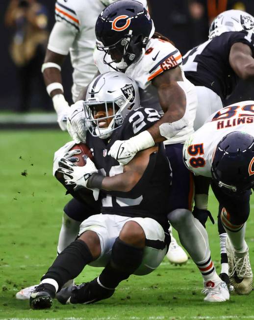 Raiders running back Josh Jacobs (28) gets stopped by Chicago Bears linebacker Danny Trevathan ...