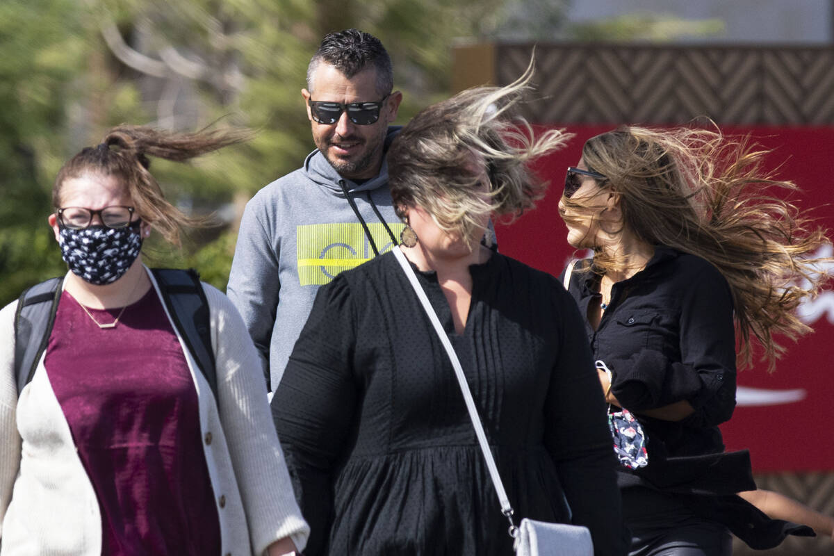 Pedestrians have their hair blown as they walk during strong winds at the corner of Las Vegas a ...