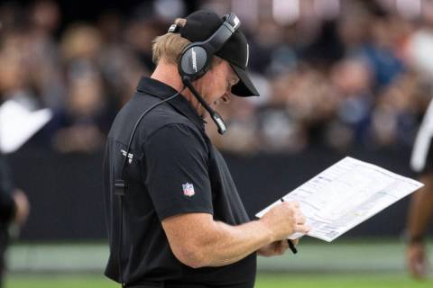 Raiders head coach Jon Gruden checks his playbook during the second half of an NFL football gam ...