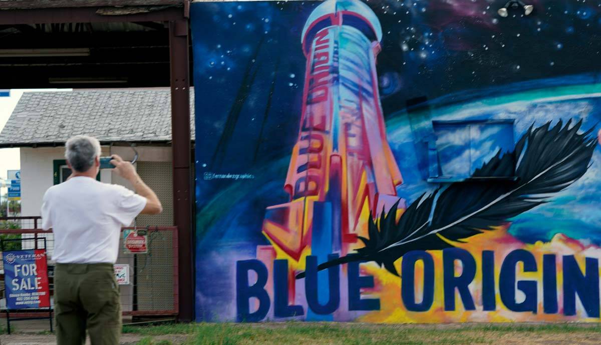 Gene Walker, of Denison, Texas, makes a photo of a Blue Origin mural on a building for sale in ...