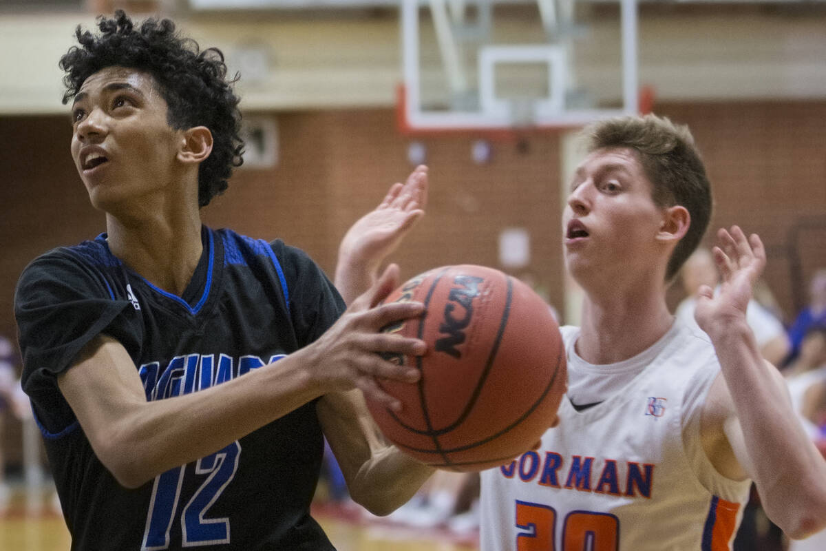 Desert Pines freshman Milos Uzan (12) drives past Bishop Gorman senior guard Noah Taitz (20) in ...