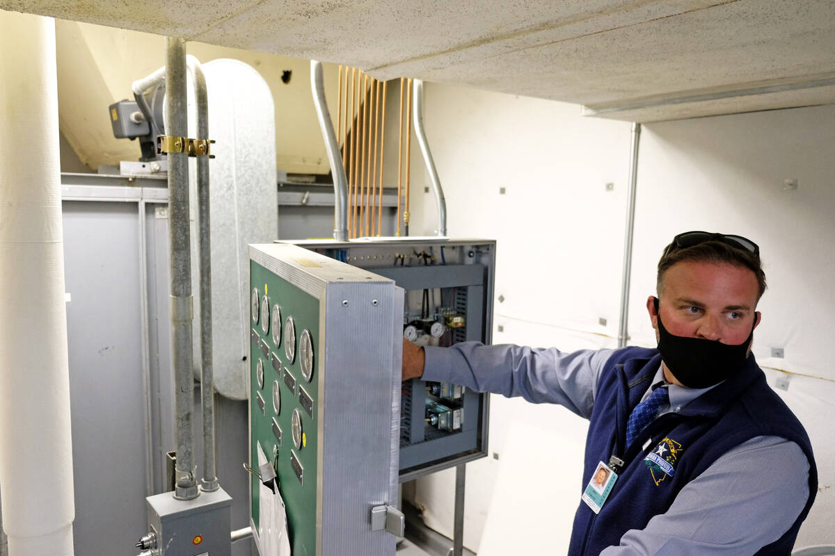 Facilities manager Jon Vietti shows the inner workings of a pneumatic thermostat controller tha ...