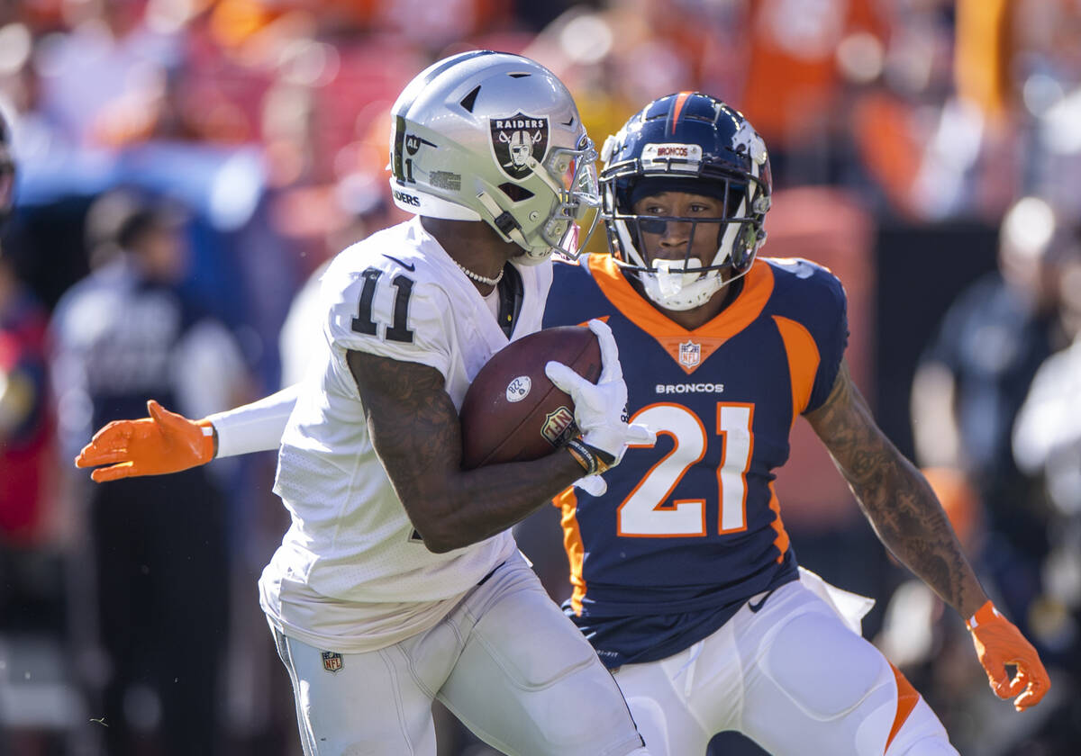 Raiders wide receiver Henry Ruggs III (11) looks to run away from Denver Broncos cornerback Ron ...