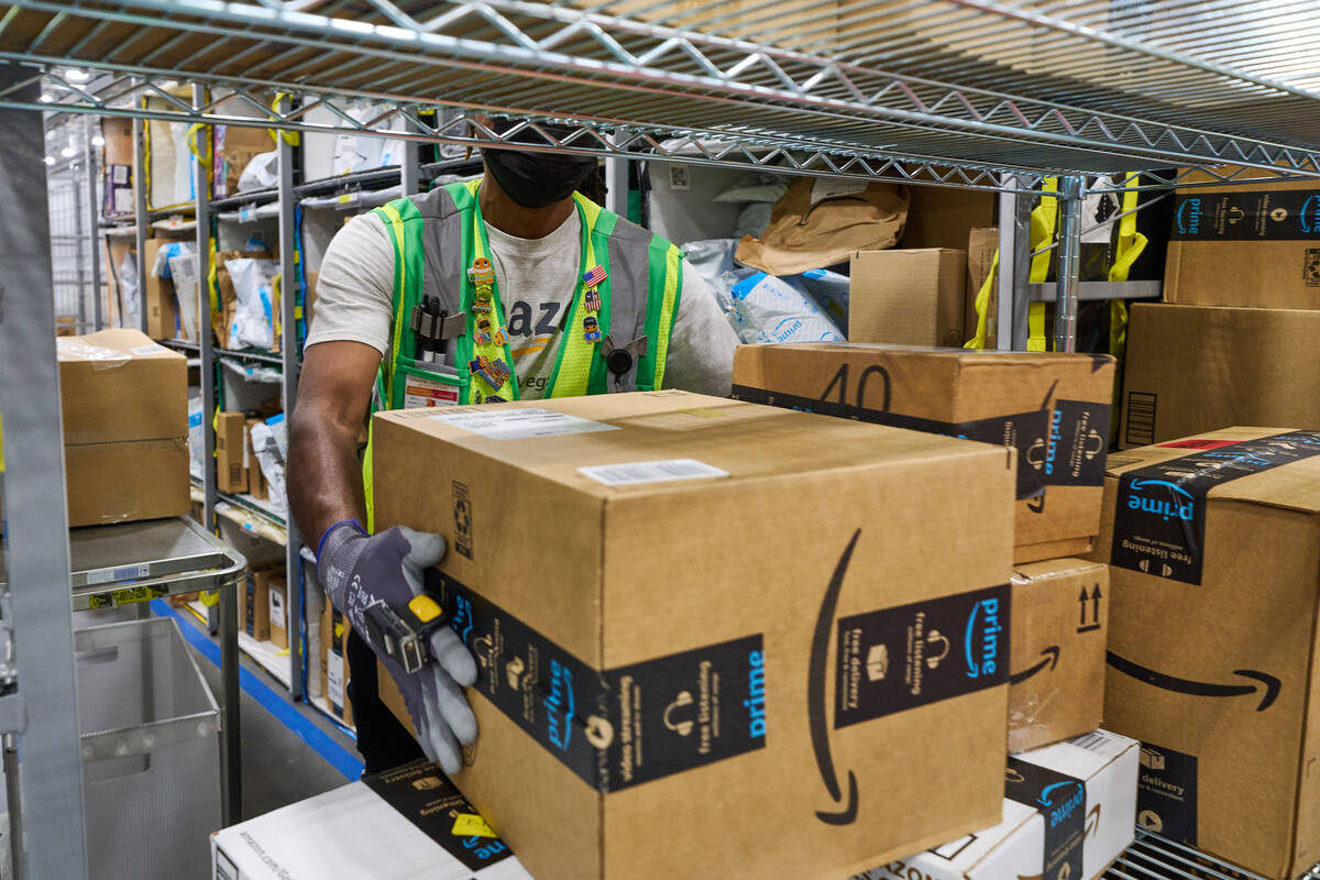 A worker handles packages at an Amazon delivery station. Amazon recently opened a new distribut ...