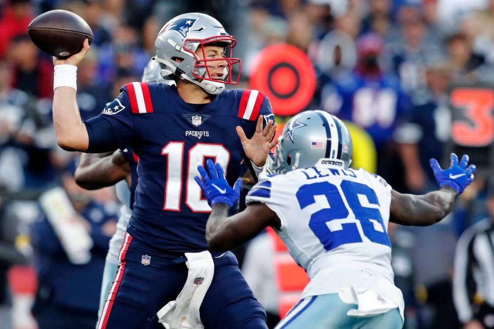New England Patriots quarterback Mac Jones (10) throws while pressured by Dallas Cowboys corner ...