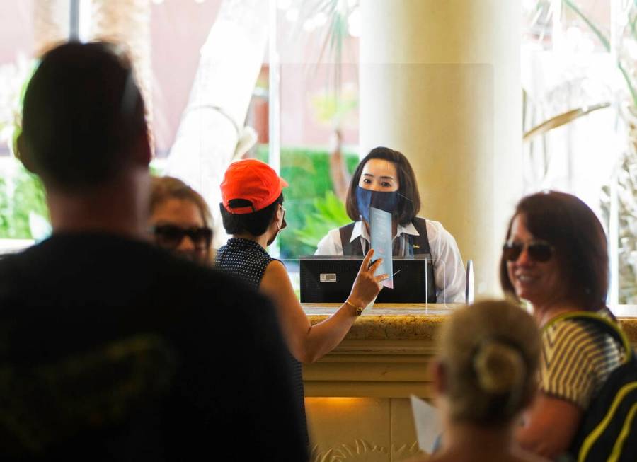 Guest service representatives wear protective masks and gloves while checking people in at TI o ...