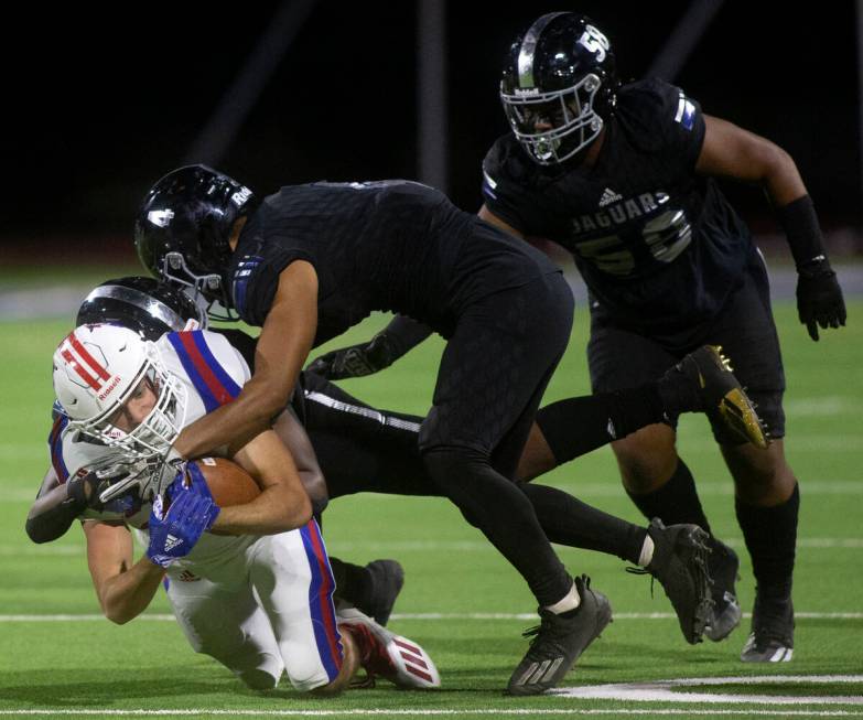 Liberty's Brody Clark (22) is tackled by Desert Pines' Landon Mccomber (25) and Leonard Ramos ( ...