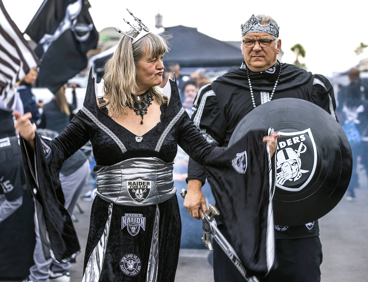 Raiders Queen Petra Thiessen walks with King Thomas Thiessen in tailgating before the first hal ...