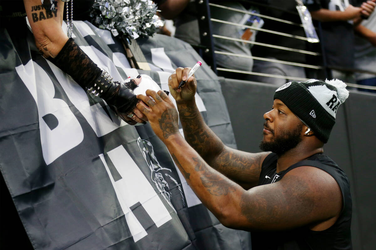 Raiders defensive tackle Quinton Jefferson (77) signs autographs before the start of a NFL foot ...