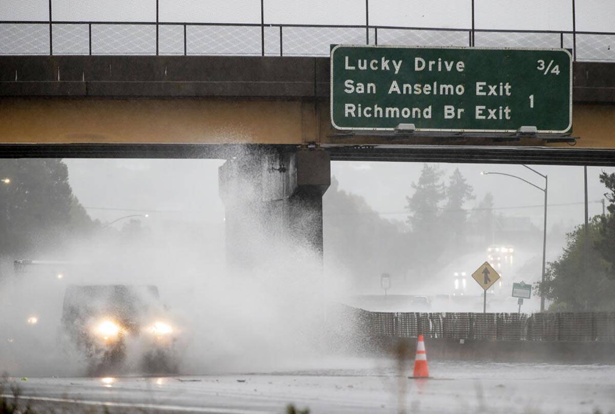 A car drives on Highway 101, which is partially flooded in Corte Madera, Calif., Sunday, Oct. 2 ...