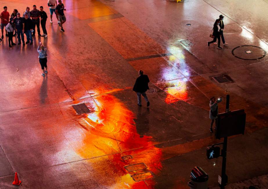 People walk around Fremont Street as rain comes down in downtown Las Vegas on Monday, Oct. 25, ...