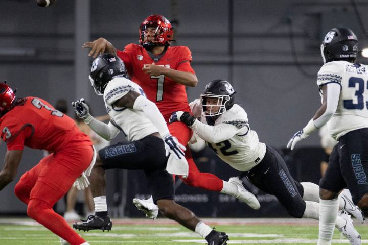 UNLV Rebels quarterback Cameron Friel (7) just gets the ball away with pressure from Utah State ...