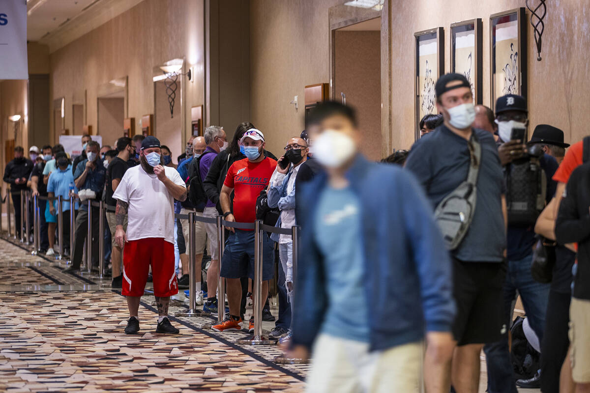 Players in masks wait in line to register for events on the first day of the World Series of Po ...