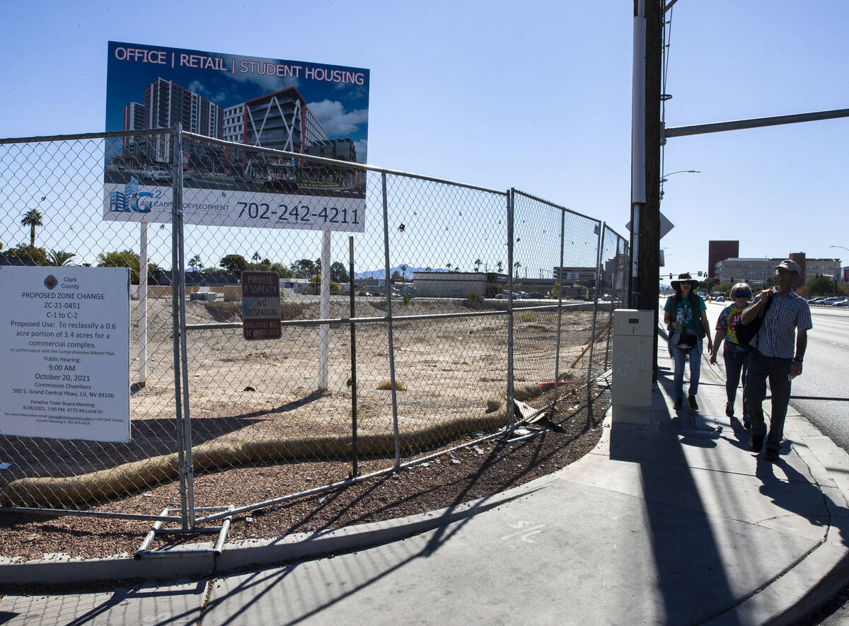 PedestrianS walk past a plot of land, left, near UNLV, on Wednesday, Oct. 27, 2021, in Las Vega ...