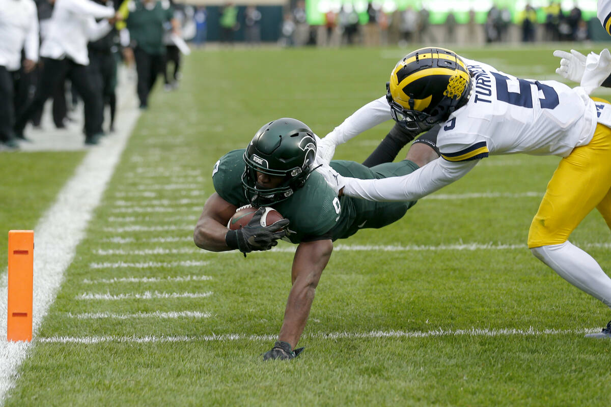 Michigan State's Kenneth Walker III, left, dives over the goal line for a touchdown against Mic ...
