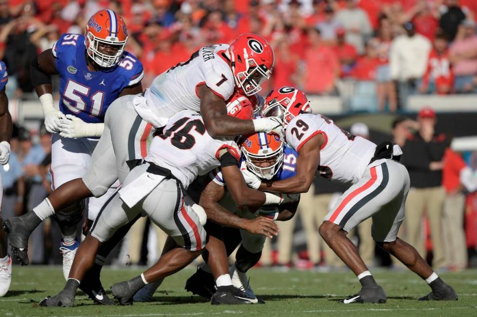 Florida quarterback Anthony Richardson (15) is tackled by Georgia defensive back Lewis Cine (16 ...