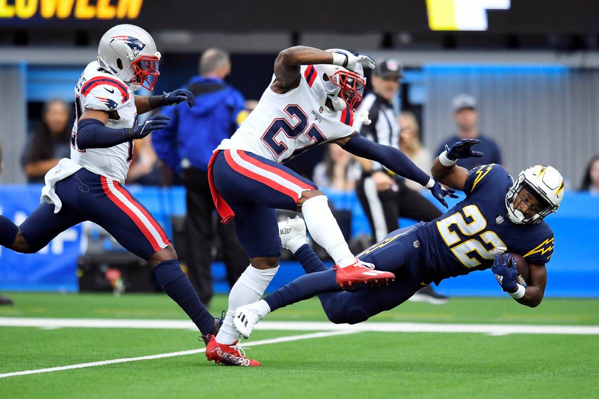 Los Angeles Chargers running back Justin Jackson (22) is tackled by New England Patriots corner ...