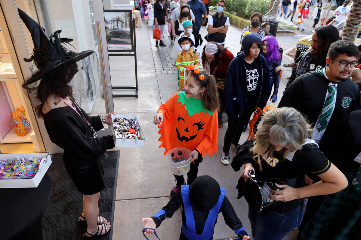 Jaylin Grady, left, hands out candy from the Pandora store during the Halloween Ghost Walk at T ...
