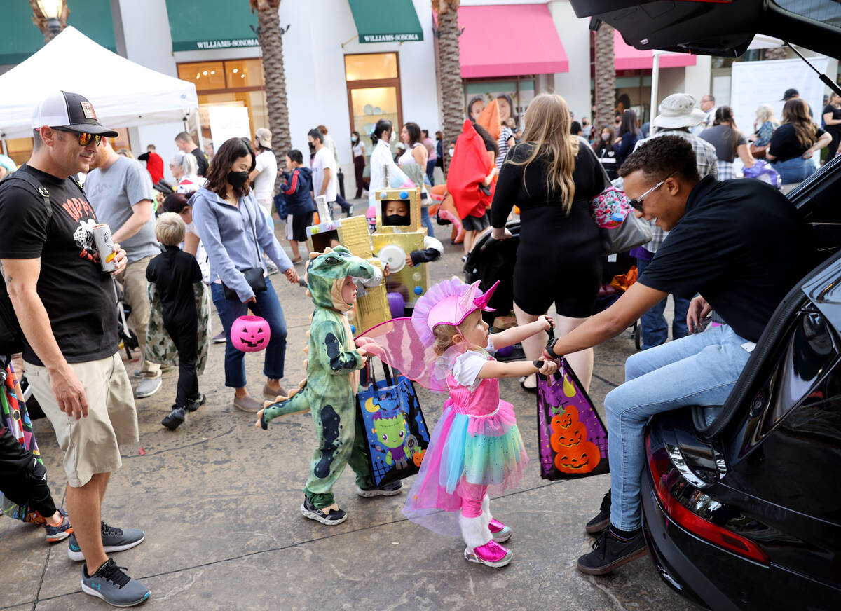Kasen, 4, and Kinsley Price, 2, of Henderson get candy from Devin Thomas of Audi Henderson duri ...