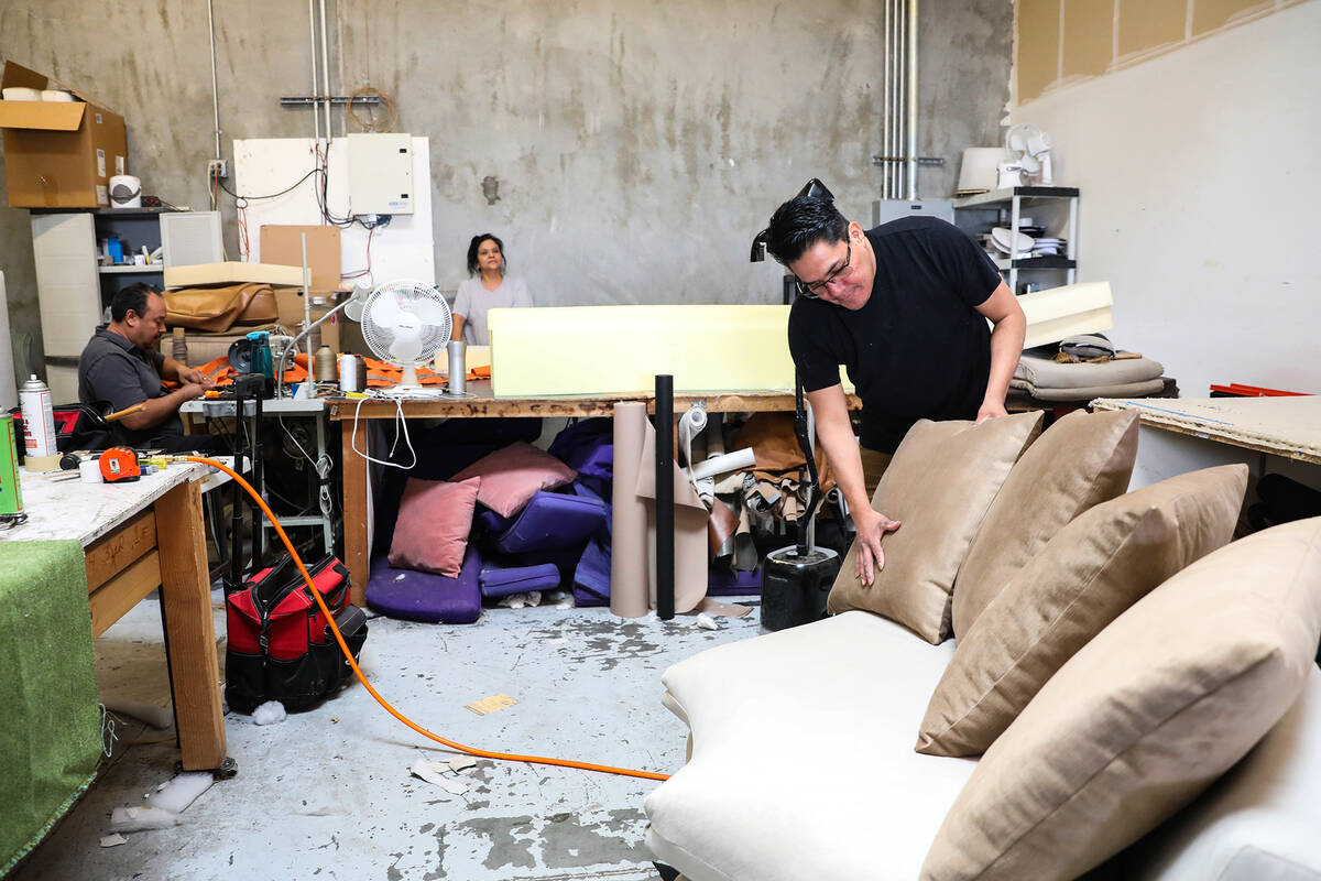 Upholster Santiago Hernandez sets a pillow on a sofa he just finished at Summerlin Upholstery i ...