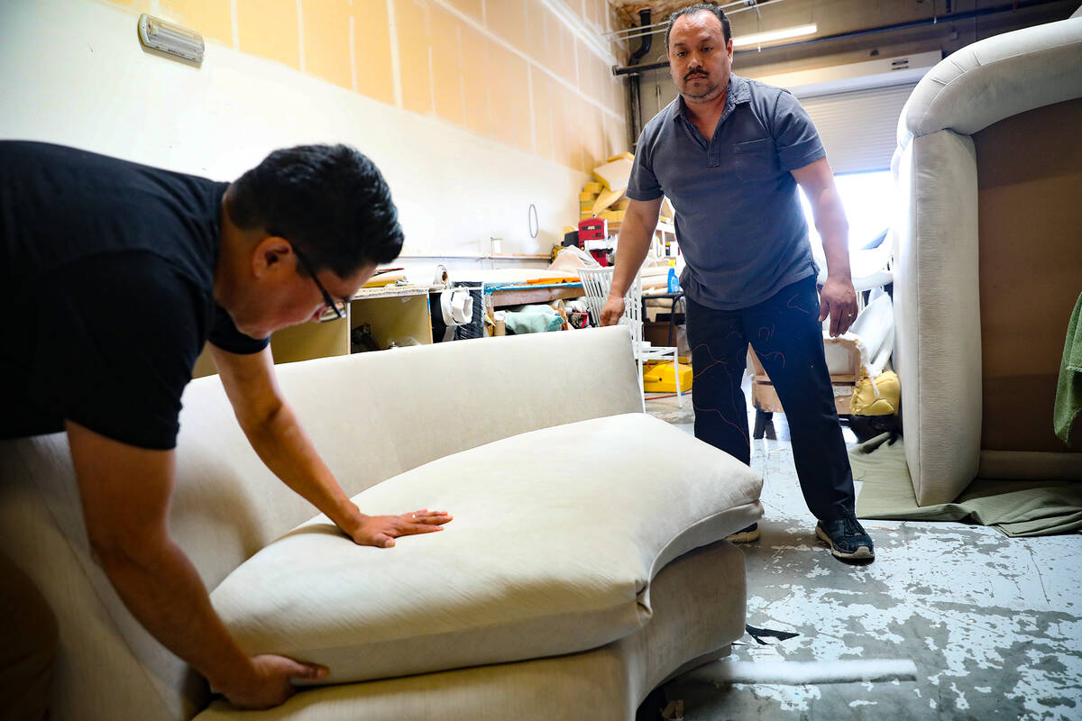 Santiago Hernandez, left, adjusts a pillow on a sofa he just finished with Jaime Molina, right, ...