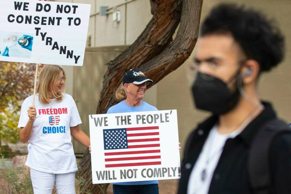 A UNLV student walks past Julie Williams and her husband Terry, both of Henderson, as they prot ...