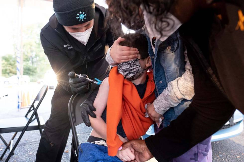 Levi Lefkove, 6, is held by his sister Leah, 9, while getting his first COVID-19 vaccine at the ...