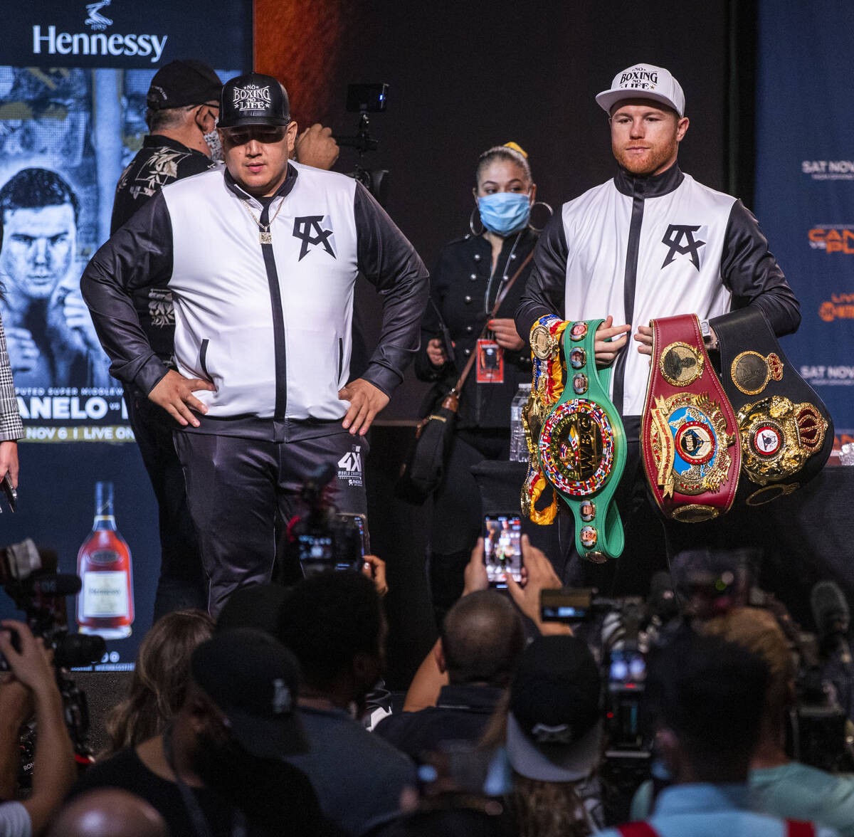 Boxer Canelo Alvarez holds his belts with trainer Eddy Reynoso standing before media members du ...