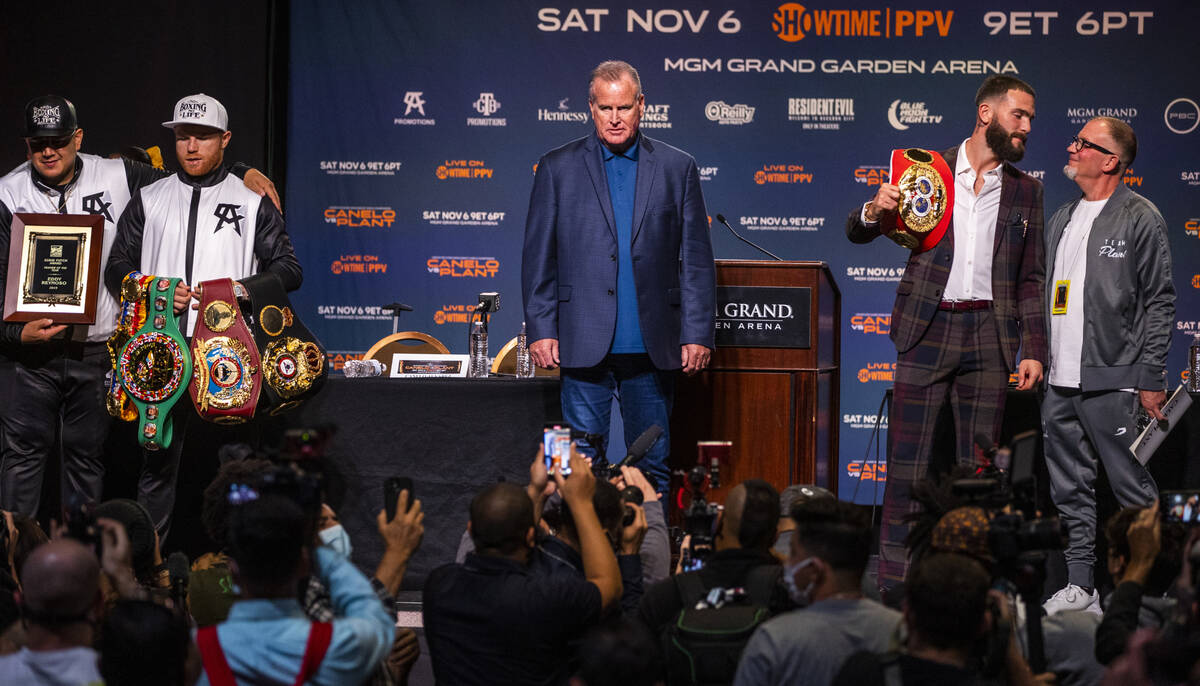 Boxer Canelo Alvarez holds his belts with trainer Eddy Reynoso, left, and Caleb Plant beside hi ...