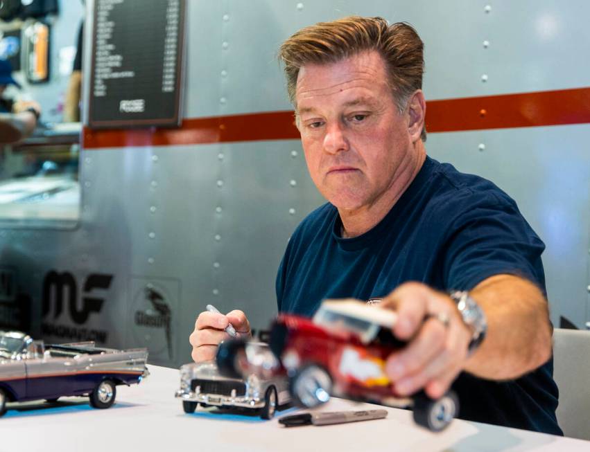 Chip Foose signs autographs on a model car at his display during SEMA at the Las Vegas Conventi ...