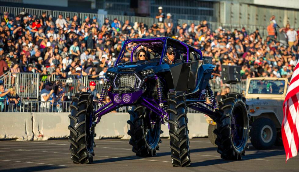A lifted car passes the fans packed into the stands during the car Cruise at SEMA Ignited from ...
