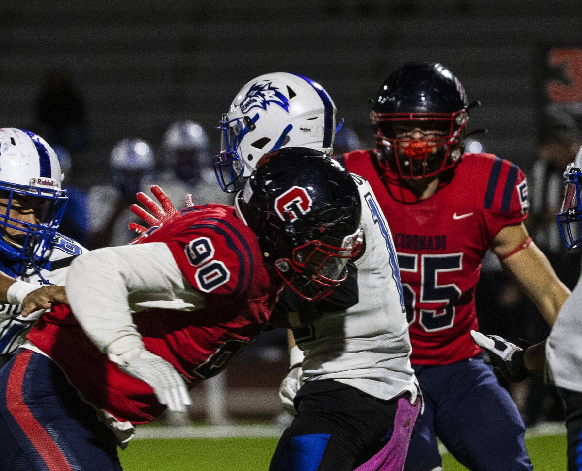 Basic wide receiver Anthony Sanitoa (1) tackled by Coronado High defensive end Bryce Echols (90 ...