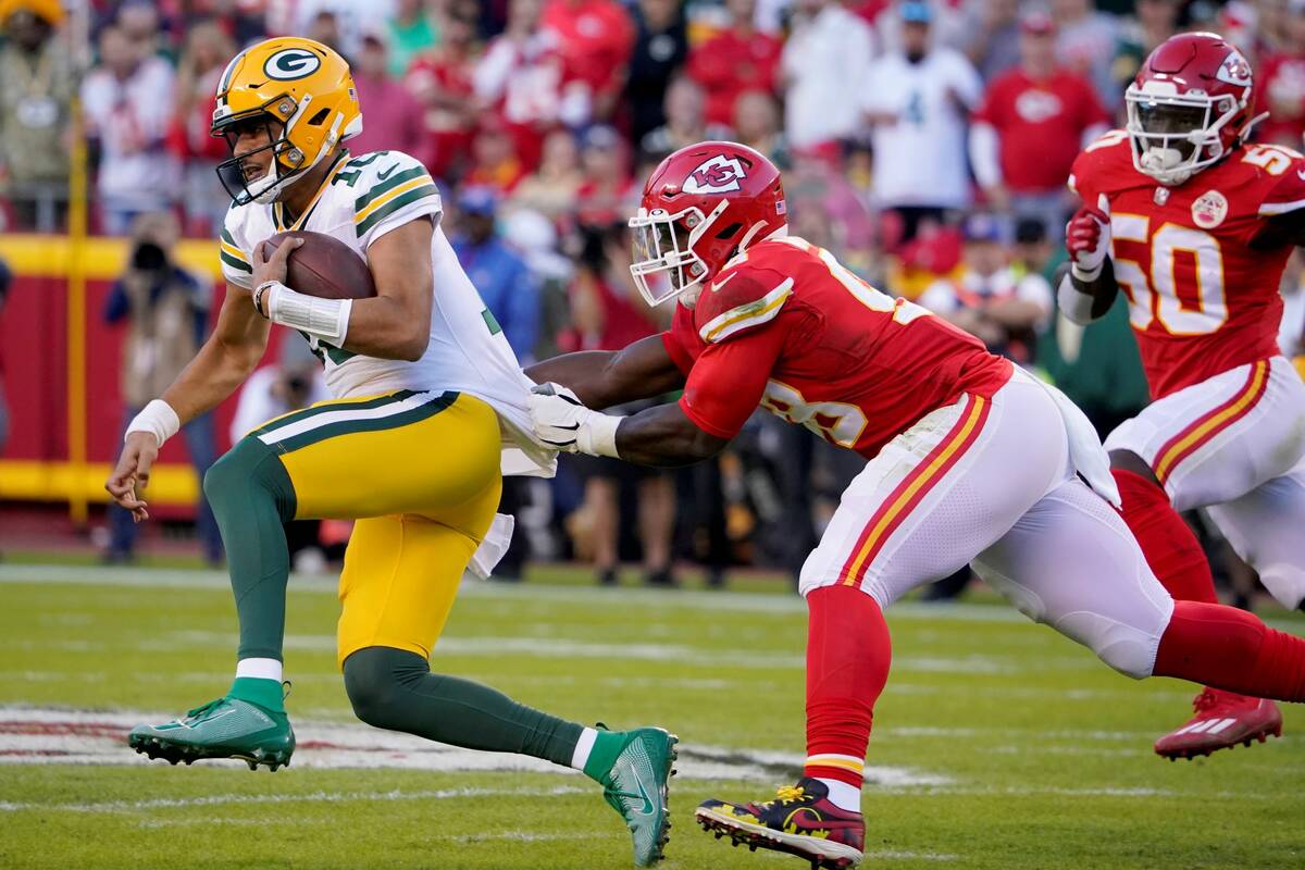 Green Bay Packers quarterback Jordan Love, left, is pulled down by Kansas City Chiefs defensive ...